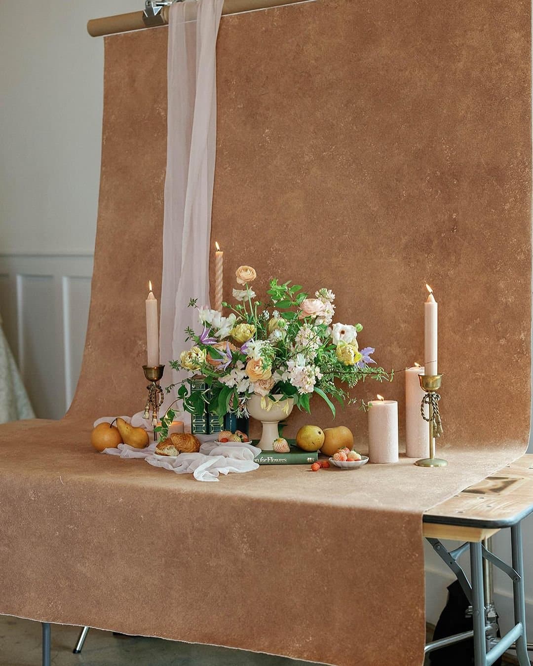 Candles, florals, and fruit styled against a hand painted backdrop